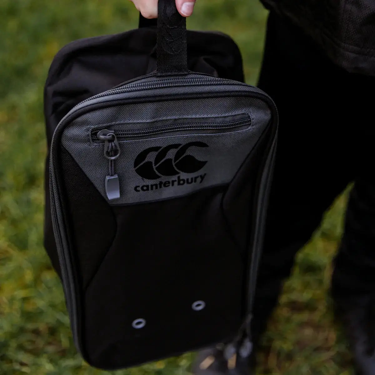 Black Canterbury boot bag held by a person on a grassy background