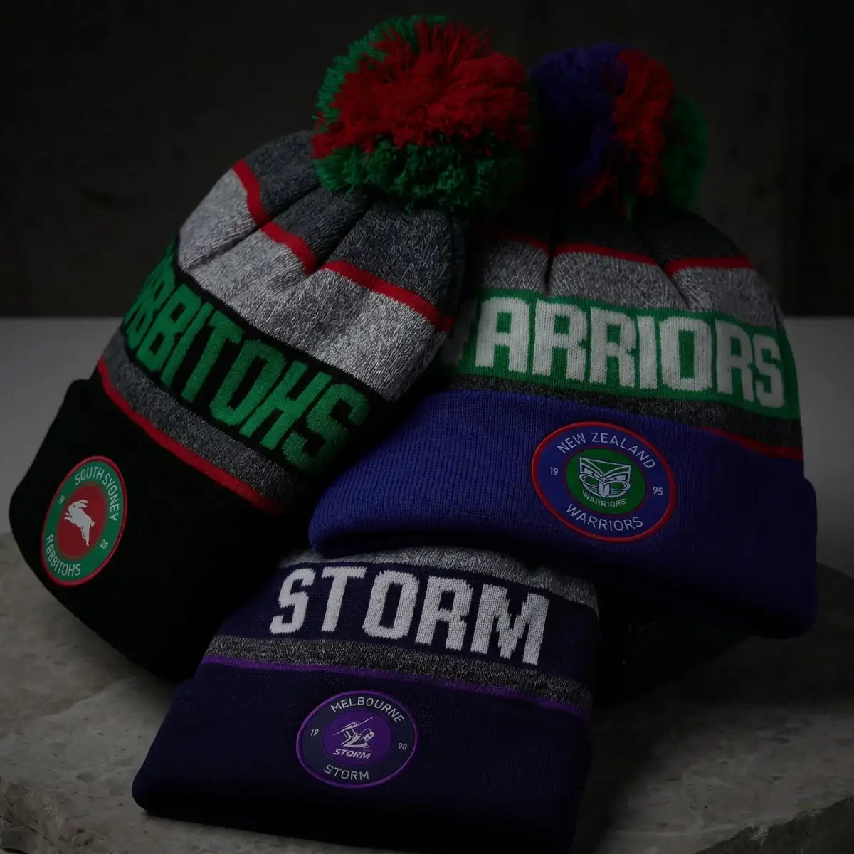 Four beanies with visible branding on a dark background